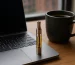 Vape de CBD con cartucho de aceite dorado junto a portátil y taza de café